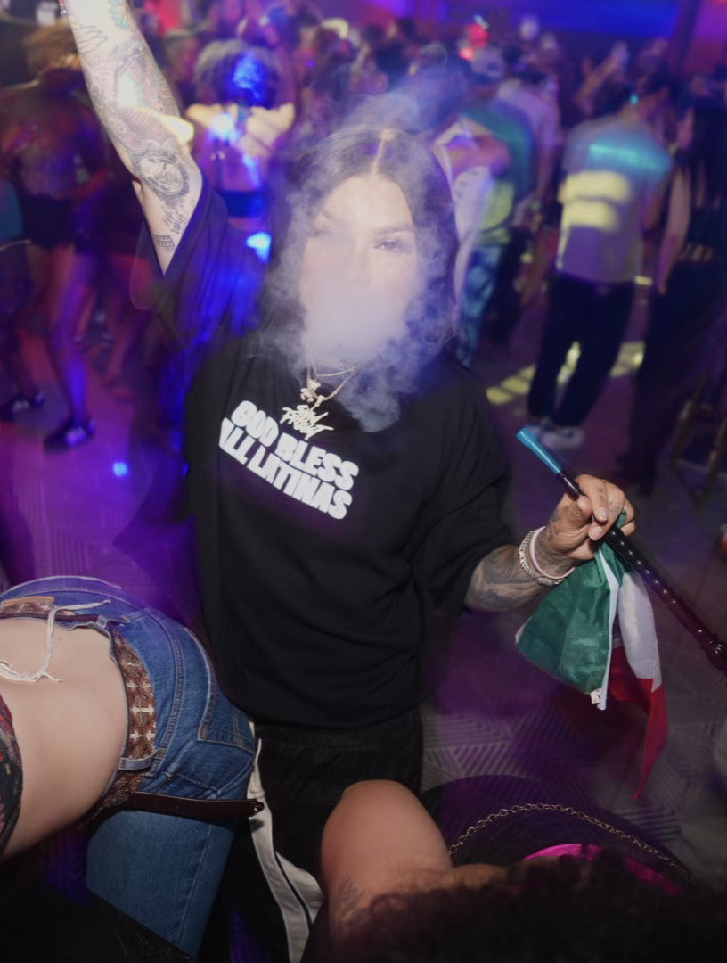 People dancing at a party with a woman holding a microphone and another person in a black shirt with text.